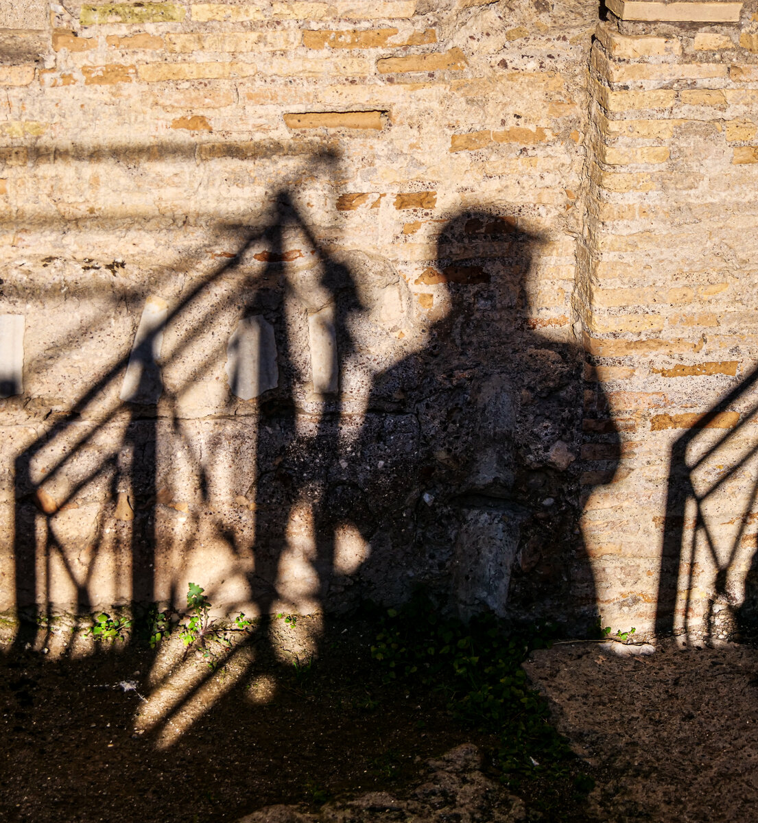 The photographer's shadow with a camera, cast on an ancient brick wall at Villa dei Quintili, Rome